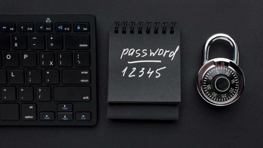 Cadenas à code et carnet noir portant un mot de passe à côté d'un clavier, pour illustrer la protection des mots de passe