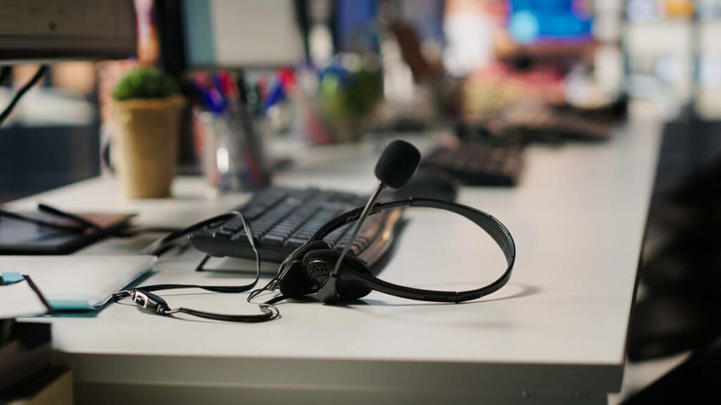 Casque avec micro posé sur le clavier d'un poste de standard téléphonique en entreprise