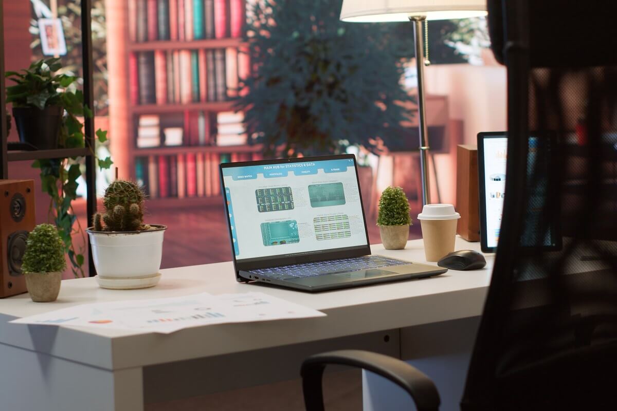 Bureau avec ordinateur portable ouvert, plantes et documents de travail
