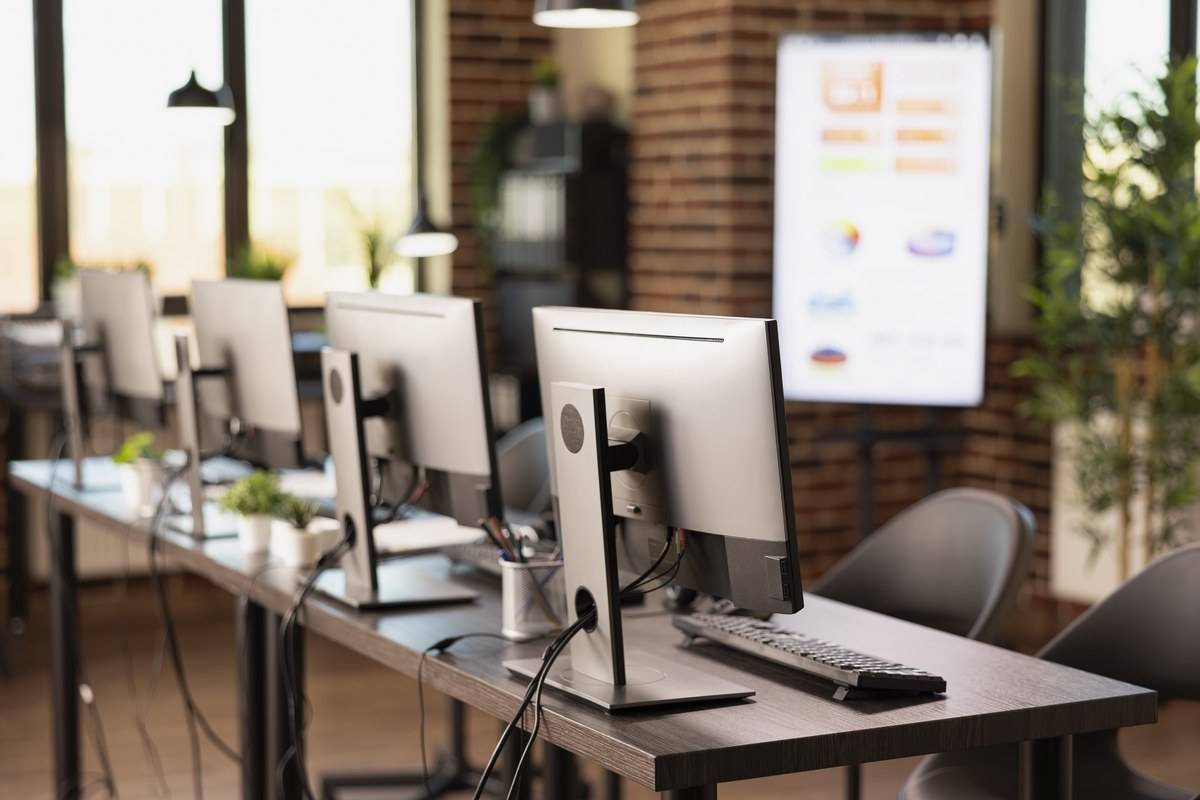Salle informatique vide avec des postes équipés d'écrans, claviers et souris