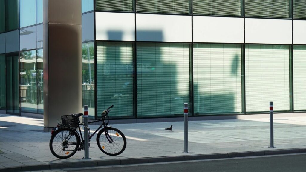 Vélo attaché à une borne devant un immeuble de bureaux vitré