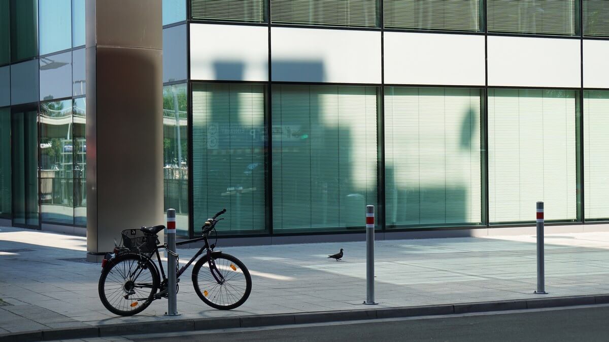 Vélo attaché à une borne devant un immeuble de bureaux vitré